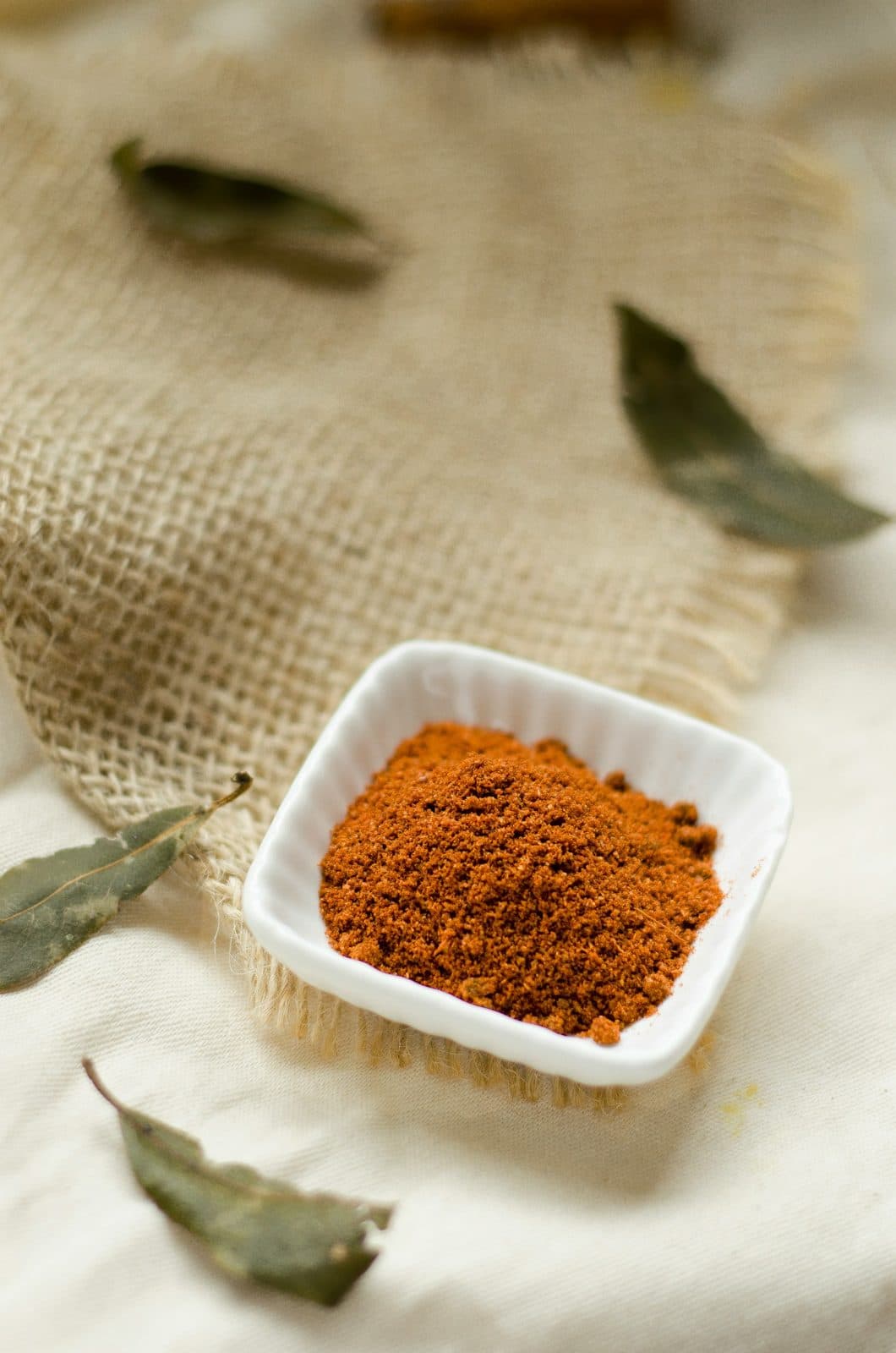 Chaat masala in a small white dish with bay leaves