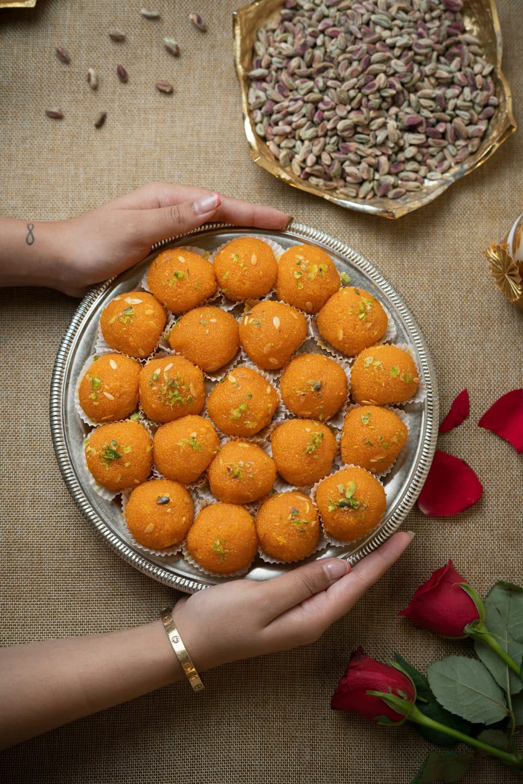 A plate of magaj laddoos held in two hands