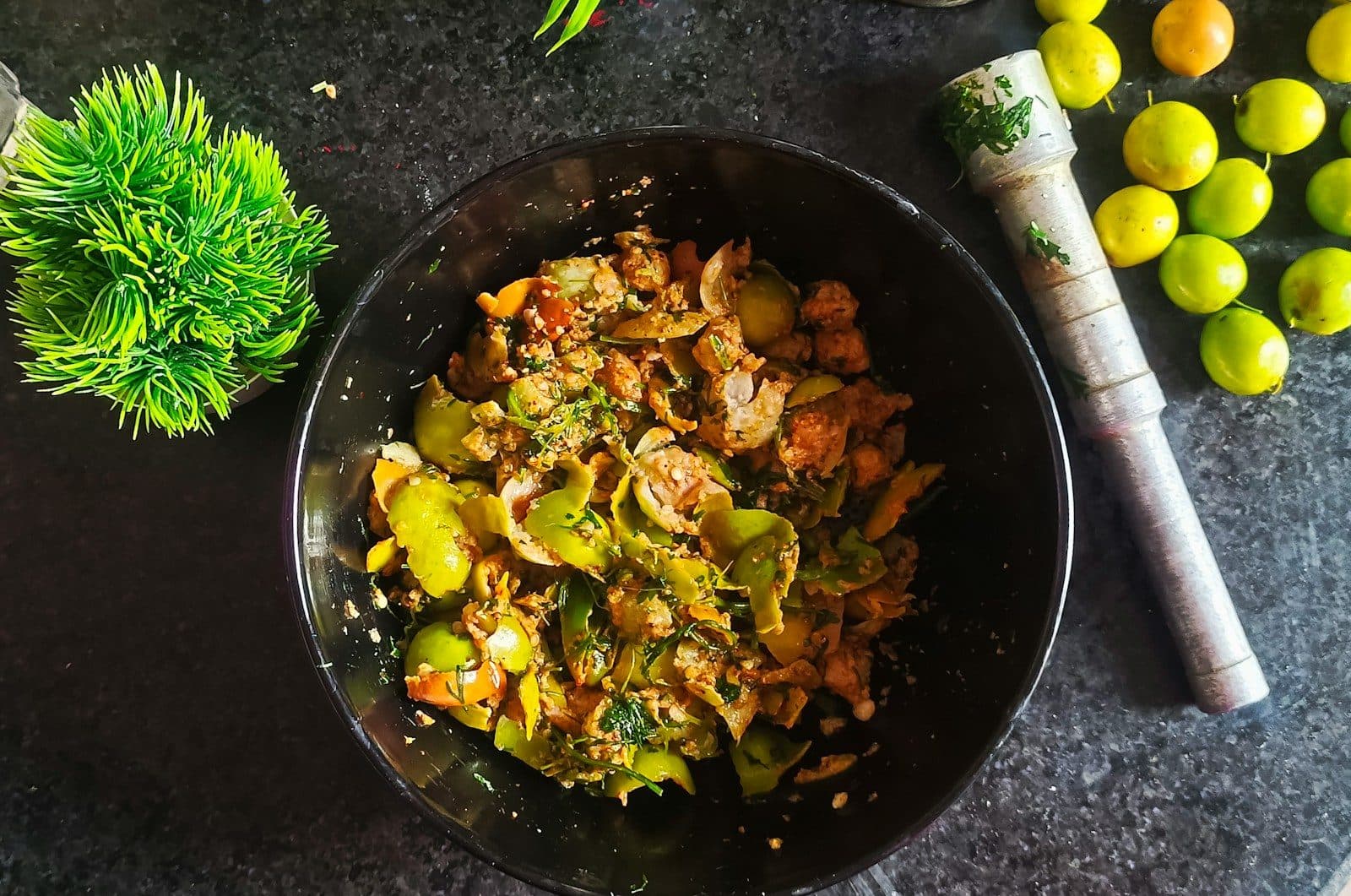 Lemon pickle in a black bowl with fresh limes